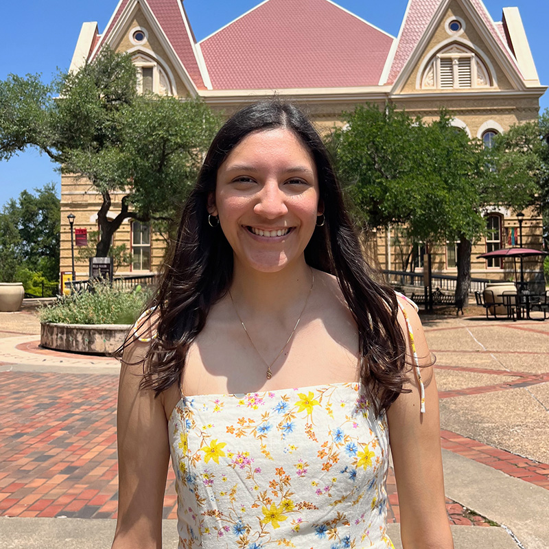 Sarah Hernandez stands in front of Old Main at Texas State University.